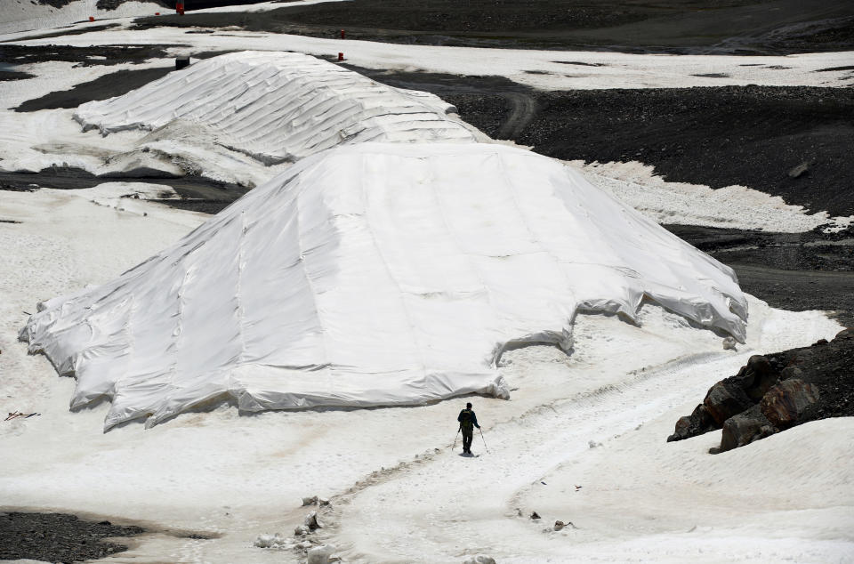 A person walks next to covered depots of snow to outlast the summer in a glacier ski resort near the village of St. Leonhard im Pitztal, Austria. (Photo: Lisi Niesner/Reuters)