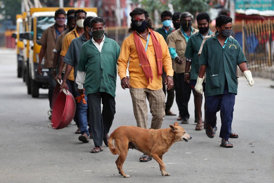 Indian municipal workers leave after working in a containment zone during lockdown in Bengaluru, India: AP