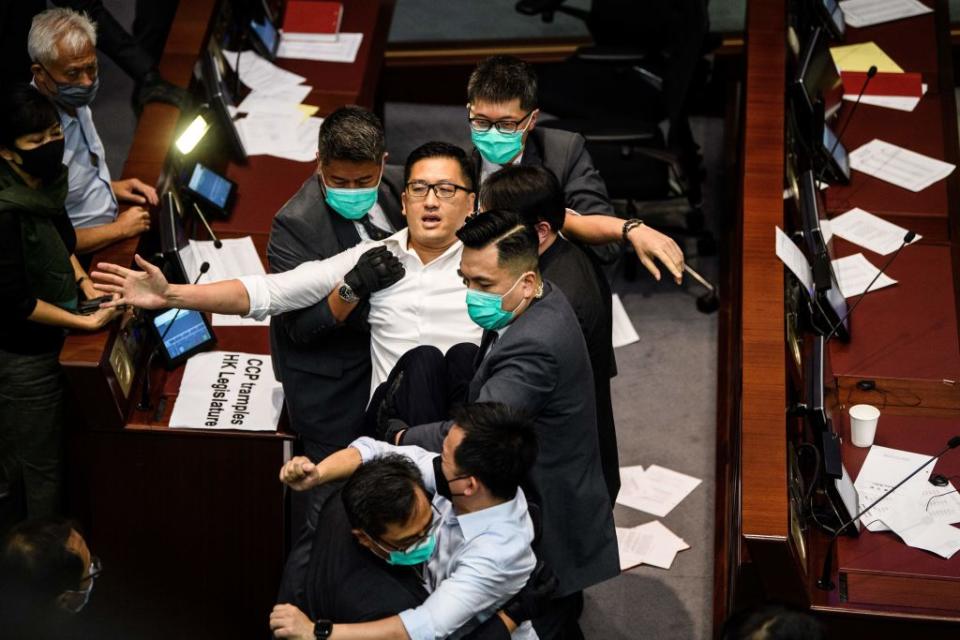 Pan-democratic politician, Lam Cheuk-ting (C) is removed by security after throwing papers torn from the Legco rulebook during a scuffle between pro-democracy and pro-Beijing lawmakers at the House Committee's election of chairpersons, at the Legislative Council in Hong Kong on May 18, 2020.<span class="copyright">ANTHONY WALLACE/AFP via Getty Images</span>