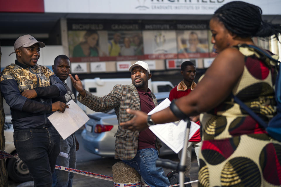 Informal vendors refused temporary working licenses speak to each other, in Johannesburg Tuesday, April 7, 2020. South Africa and more than half of Africa's 54 countries have imposed lockdowns, curfews, travel bans or other restrictions to try to contain the spread of COVID-19. The new coronavirus causes mild or moderate symptoms for most people, but for some, especially older adults and people with existing health problems, it can cause more severe illness or death.(AP Photo/Jerome Delay)