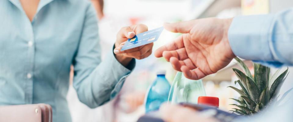 Woman at the supermarket checkout, she is paying using a credit card