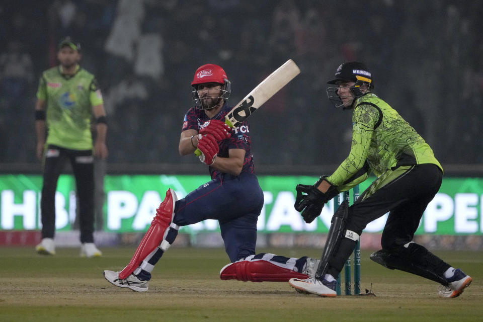 Islamabad United' Salaman Ali Agha, center, plays a shot as Lahore Qalandars' Lorcan Tucker, right, watches during the Pakistan Super League T20 cricket match between Islamabad United and Lahore Qalandars, in Lahore, Pakistan Saturday, Feb. 17, 2024. (AP Photo/K.M. Chaudary)