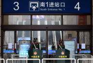 Oficiales paramilitares chinos hacen guardia con sus máscaras en una de las entradas de la estación de tren cerrada de Hankou. (Foto: China Daily / Reuters).