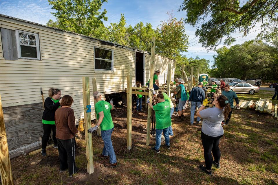 Volunteers from Publix and VISTE work to install a deck and a ramp at the mobile home owned by the Persaud family in the Kathleen area. Habitat for Humanity is contributing volunteer work and supplies for the project.