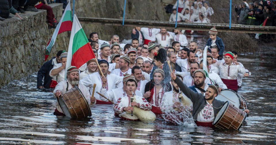 Bulgarians sing, play bagpipes and chain dance in the icy waters of the Tundzha river during Epiphany, in Kalofer, Bulgaria, Monday, Jan. 6, 2020. Thousands of Orthodox Christian worshippers plunged into the icy waters of rivers and lakes across Bulgaria on Monday to retrieve crucifixes tossed by priests in ceremonies commemorating the baptism of Jesus Christ. In the mountain city of Kalofer, in central Bulgaria, dozens of men dressed in white embroidered shirts waded into the frigid Tundzha River waving national flags and singing folk songs. (AP Photo)