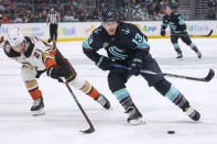 Seattle Kraken left wing Brandon Tanev (13) moves the puck as Anaheim Ducks defenseman Gustav Lindstrom (28) defends during the first period of an NHL hockey game Thursday, March 28, 2024, in Seattle. (AP Photo/Jason Redmond)