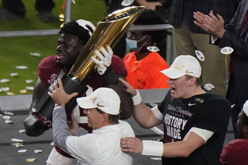 Alabama head coach Nick Saban and offensive lineman Alex Leatherwood hold the trophy after their win against Ohio State in an NCAA College Football Playoff national championship game, Tuesday, Jan. 12, 2021, in Miami Gardens, Fla. Alabama won 52-24. (AP Photo/Wilfredo Lee)