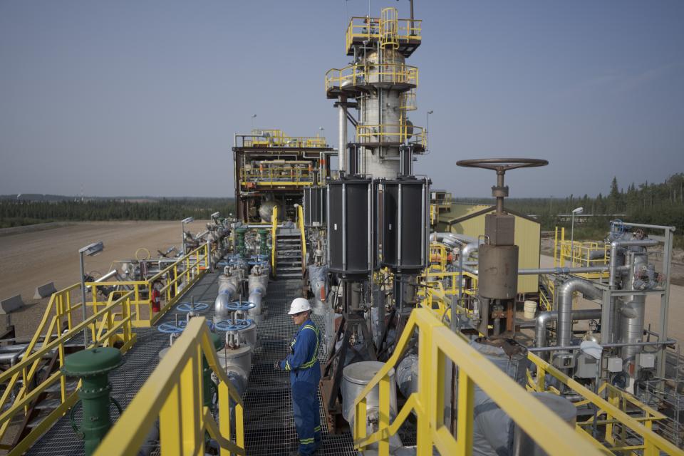 A worker stands on a steam-assisted gravity drainage pad at Cenovus' Sunrise oil facility northeast of Fort McMurray on Thursday, Aug. 31, 2023. Wildfires are bringing fresh scrutiny to Canada's fossil fuel dominance, its environmentally friendly image and the viability of becoming carbon neutral by 2050. (AP Photo/Victor R. Caivano)