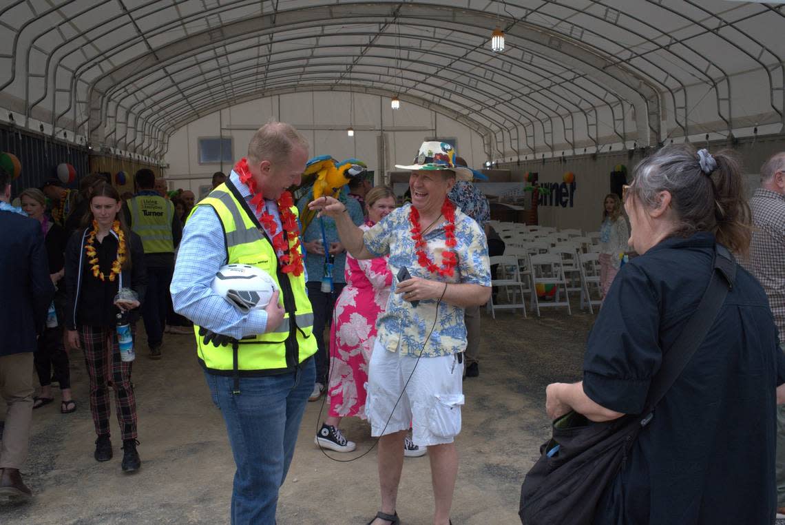 Clifton Bencke, right, shows off a parrot named Captain Flint during a ceremony on Wednesday, May 8, 2024, at the site of the under-construction Margaritaville Hotel in western Kansas City, Kansas.