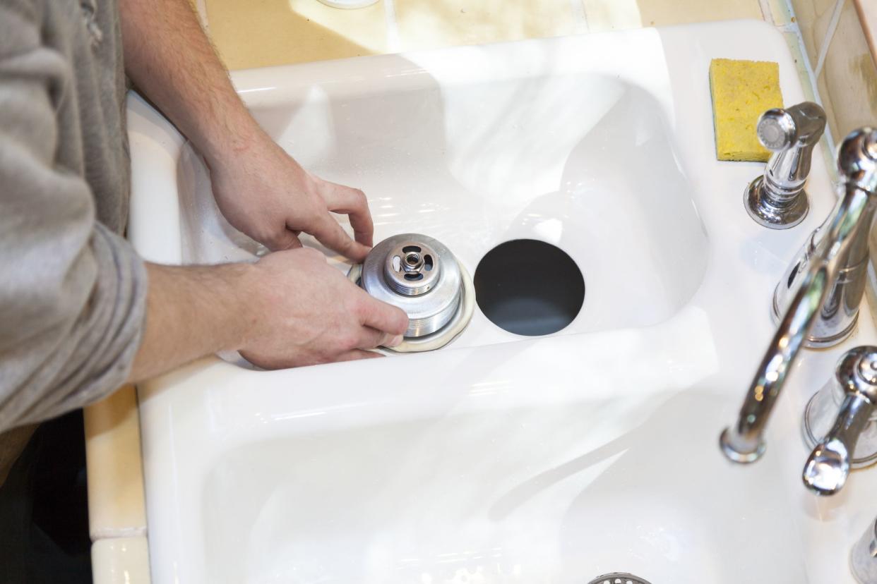 Man installing garbage disposal in home.