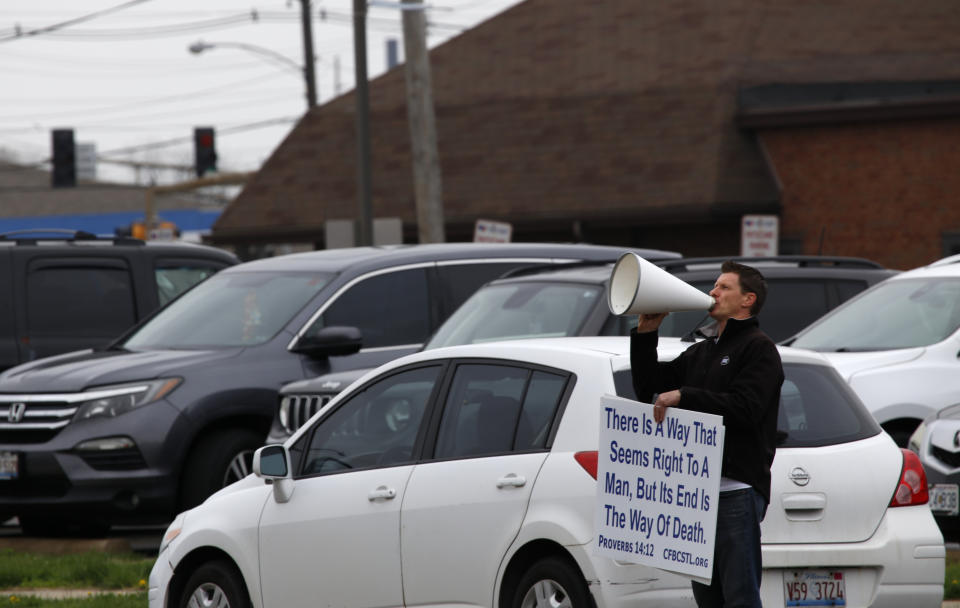 A pastor uses a megaphone to implore women not to get abortions on Tuesday, April 12, 2022, outside the Hope Clinic for Women in Granite City, Ill. "Don't murder your baby!" he shouted. The pastor, whose church is across the state line in the St. Louis area, declined to give his name but said he stands outside the clinic and does this often. More women from Missouri and states much farther away are coming to Illinois for abortions, as more states restrict that kind of care. (AP Photo/Martha Irvine)
