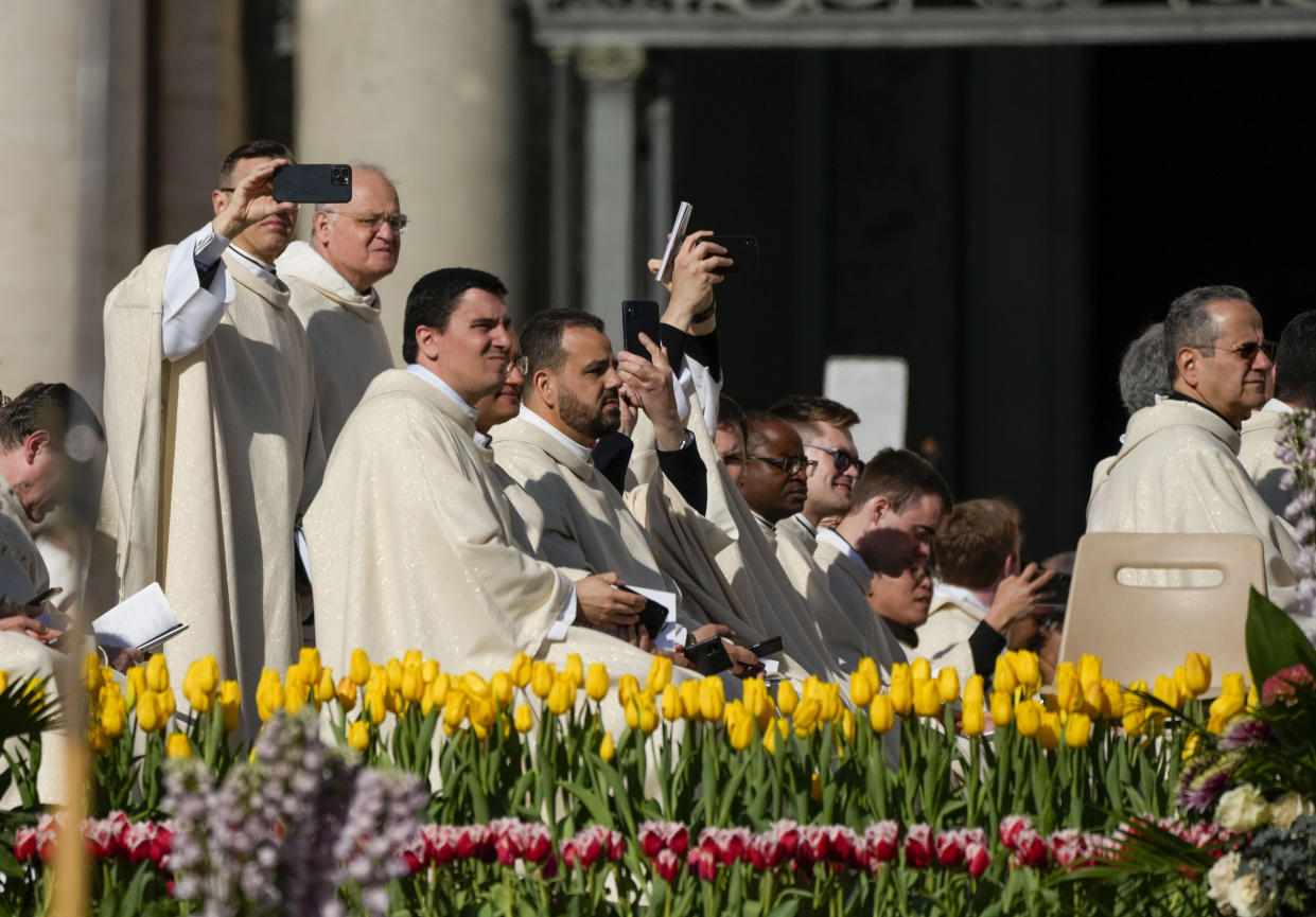 Priests take pictures in St. Peter's Square at The Vatican where Pope Francis will celebrate the Easter Sunday mass, Sunday, April 9, 2023. (AP Photo/Alessandra Tarantino)