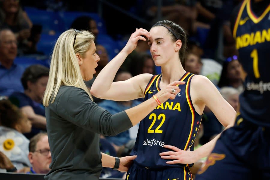 CORRECTS FROM CAITLYN TO CAITLIN – Indiana Fever head coach Christine Sides, left, talks to Fever guard Caitlin Clark (22) as they play the Dallas Wings during the first half of an WNBA basketball game in Arlington, Texas, Friday, May 3, 2024. (AP Photo/Michael Ainsworth)