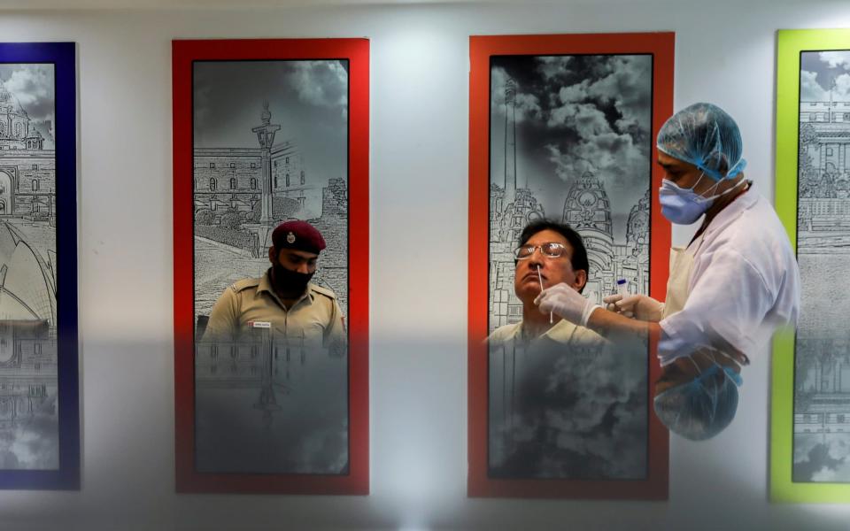 A healthcare worker wearing a protective face mask collects a swab sample from a man as India's coronavirus pandemic accelerates - REUTERS/Anushree Fadnavis