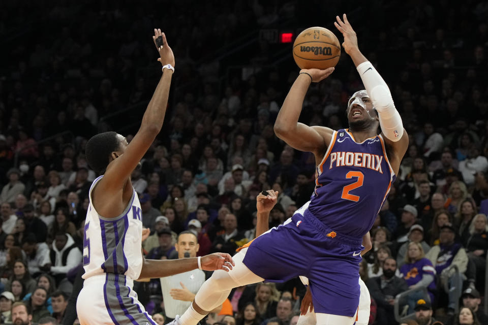 Phoenix Suns forward Josh Okogie (2) shoots off balance over Sacramento Kings guard De'Aaron Fox during the second half of an NBA basketball game, Tuesday, Feb. 14, 2023, in Phoenix. The Suns won 120-109. (AP Photo/Rick Scuteri)