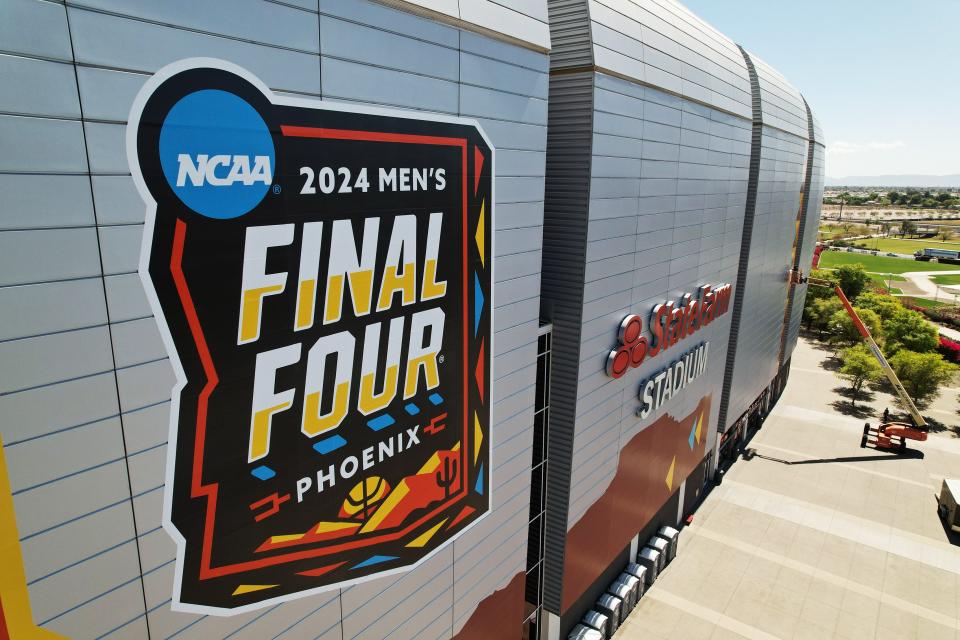 Mar 25, 2024; Glendale, Ariz., U.S.; Workers install logos on the exterior of State Farm Stadium in preparations for the Final Four April 6-8. Mandatory Credit: Michael Chow-Arizona Republic