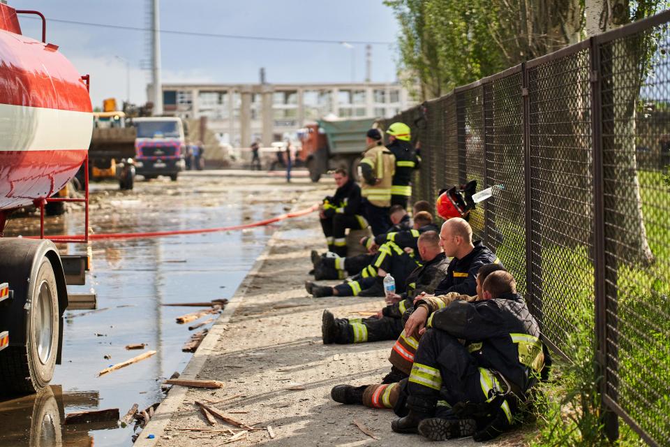 Firefighters rest during their intervention at a medical facility, the site of a missile strike, in the city of Dnipro on 26 May 2023, amid the Russian invasion of Ukraine (AFP via Getty Images)