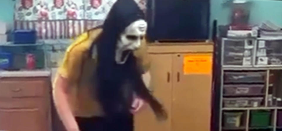 A day care worker from Lil' Blessings Child Care wearing a Ghostface mask scaring a room full of children.  (via Facebook)