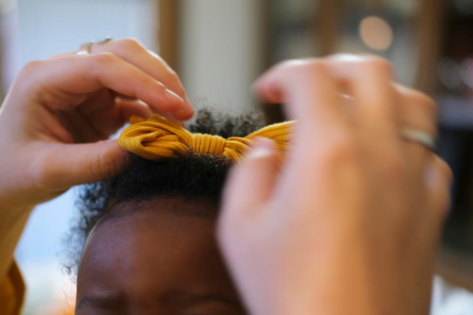 Foster mom, Cheyenne Wild, attended a workshop by The Hair Initiative, which  provides education to foster and adoptive parents for proper care and hygiene of highly textured hair. Cheyenne puts a bow in Payley's  hair to get ready for the day. Saturday, November 13, 2021.