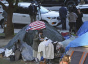 FILE - In this March 24, 2021, file photo a woman eats at her tent at the Echo Park homeless encampment at Echo Park Lake in Los Angeles. California Gov. Gavin Newsom announced a $12 billion plan Tuesday, May 11 to confront the state's homelessness crisis. (AP Photo/Damian Dovarganes, File)