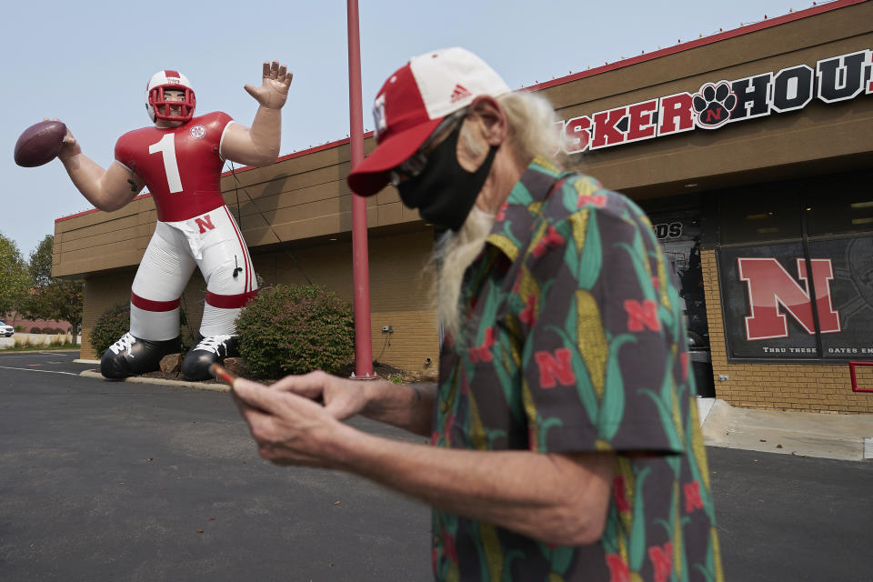 A Nebraska fan stops to take a picture of a giant inflatable football player standing in front of the Husker Hounds sports apparel store in Omaha, Neb., Wednesday, Sept. 16, 2020. It was put up Wednesday after the Big Ten conference changed course Wednesday and said it plans to begin its NCAA college football season the weekend of Oct. 23-24. Each team will have an eight-game schedule. (AP Photo/Nati Harnik)