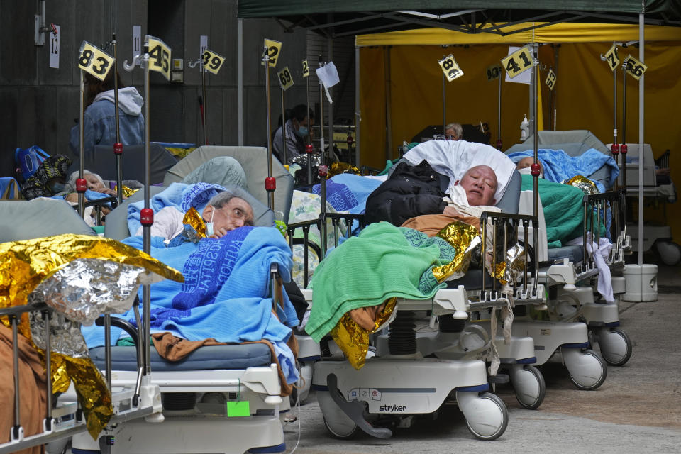 Patients lie on hospital beds as they wait at a temporary holding area outside Caritas Medical Centre in Hong Kong Wednesday, Feb. 16, 2022. There was visible evidence that Hong Kong hospitals were becoming overwhelmed by the latest Covid surge, with patients on stretchers and in tents being seen to by medical personnel on Wednesday outside the Caritas hospital. (AP Photo Vincent Yu)