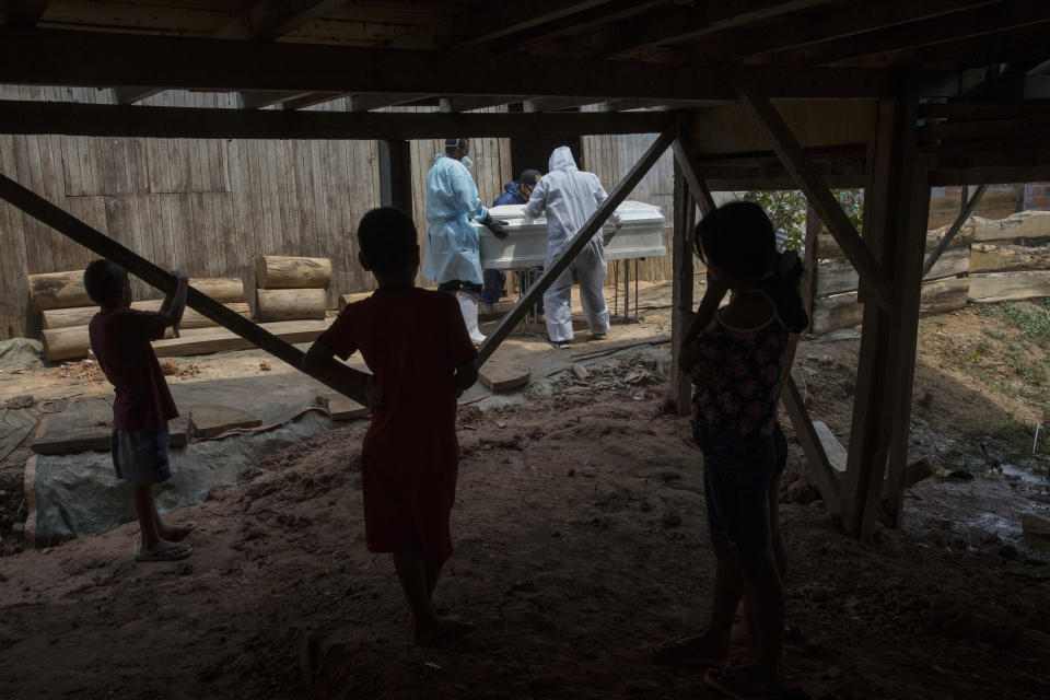 Tres niños observan mientras un grupo de operarios gubernamentales retiran el cuerpo de Susana Cifuentes, quien murió por síntomas relacionados con el coronavirus a los 71 años, en la comunidad indígena Shipibo en Pucallpa, en la región peruana de Ucayali, el 31 de agosto de 2020. Los Shipibo habían tratado de evitar la llegada del virus bloqueando carreteras y aislándose. Pero en mayo muchos empezaron a tener fiebre, tos, dificultad para respirar y dolores de cabeza. (AP Foto/Rodrigo Abd)