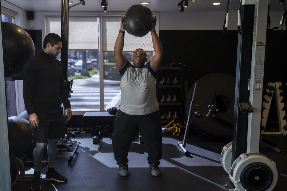 John Simon, a teenager who had a bariatric surgery in 2022, exercises with his trainer Chris Robles at El Workout Fitness in Los Angeles, Monday, March 13, 2023. (AP Photo/Jae C. Hong)