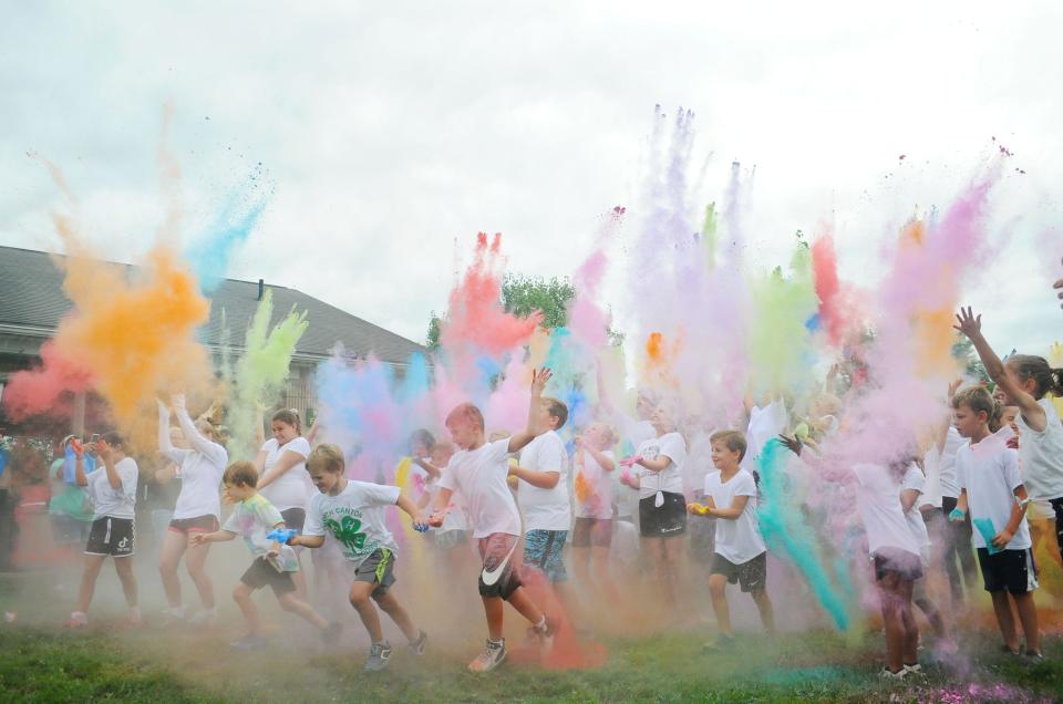 Children throw colored powder in the air at the start of the Carnation Youth Color Run on Tuesday, Aug. 9, 2022, at Alliance First Christian Church in Washington Township.