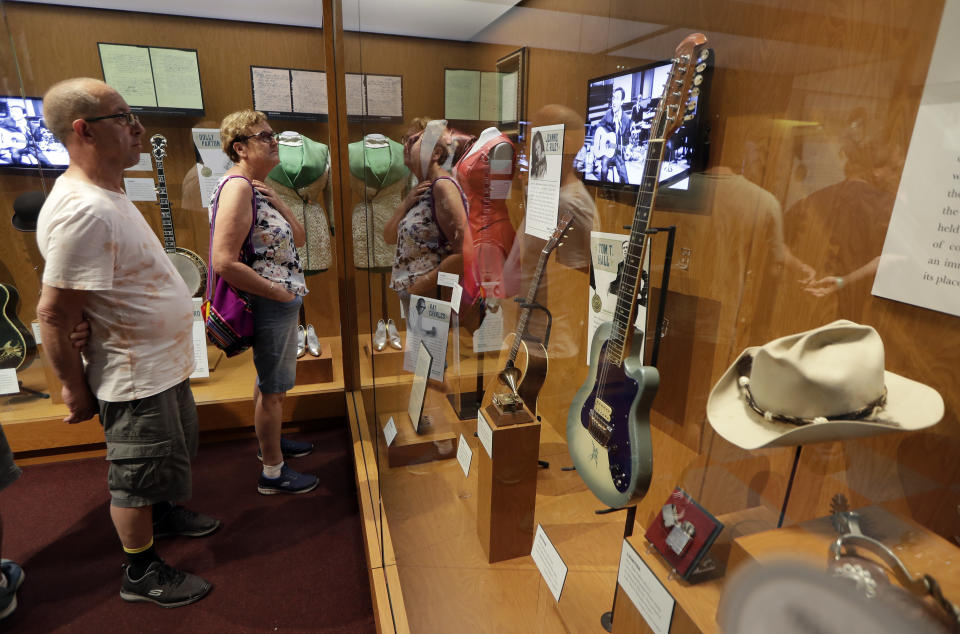 FILE - In this May 25, 2018 photo, visitors to the Country Music Hall of Fame and Museum in Nashville, Tenn. view the the Outlaws & Armadillos exhibit. Tourism comes alive in the Music City come summer, and many of the city's Nashville-based stars enjoying playing tourist, too. (AP Photo/Mark Humphrey, File)