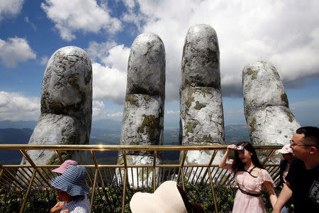 Tourists walk past giant hand structure on Gold Bridge on Ba Na hill near Danang city, Vietnam August 1, 2018. REUTERS/Kham