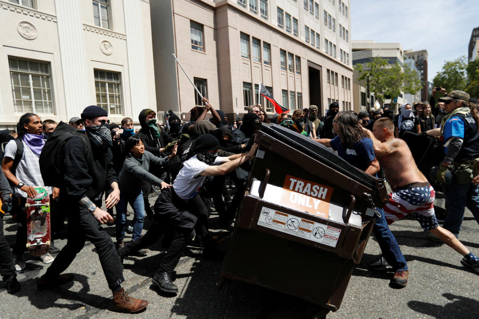 Demonstrators push a garbage container toward each other during a rally in Berkeley