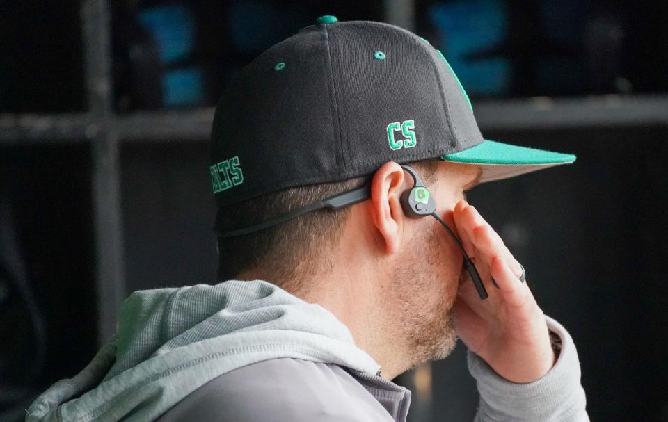 Clear Fork assistant coach Mark Lind covers his mouth while calling a pitch using an electronic communication device that was approved by the OHSAA and NFHS over the summer.