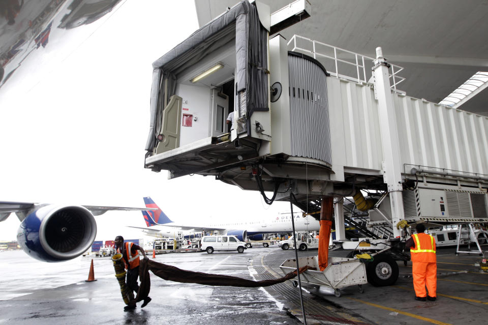 In this Wednesday, Aug. 1 2012 photo, Delta Air Lines ramp agents prepare to attach the gateway to an arriving airplane at JFK International airport in New York. Travelers still have to put up with packed planes, rising fees and unpredictable security lines, but they are missing fewer business meetings or chances to tuck their kids into bed. Nearly 84 percent of domestic flights arrived within 15 minutes of their schedule time in the first half of the year, the best performance since the government started tracking such data in 1988. (AP Photo/Mary Altaffer)