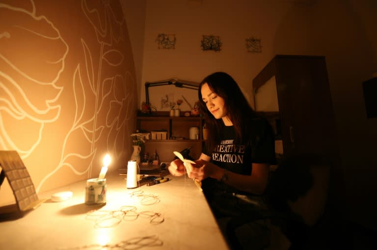 Une créatrice travaille à la lueur de bougies dans son atelier du théâtre de marionnettes de Kiev, pendant une panne d'électricité partielle, le 6 juin 2024 en Ukraine (Anatolii STEPANOV)