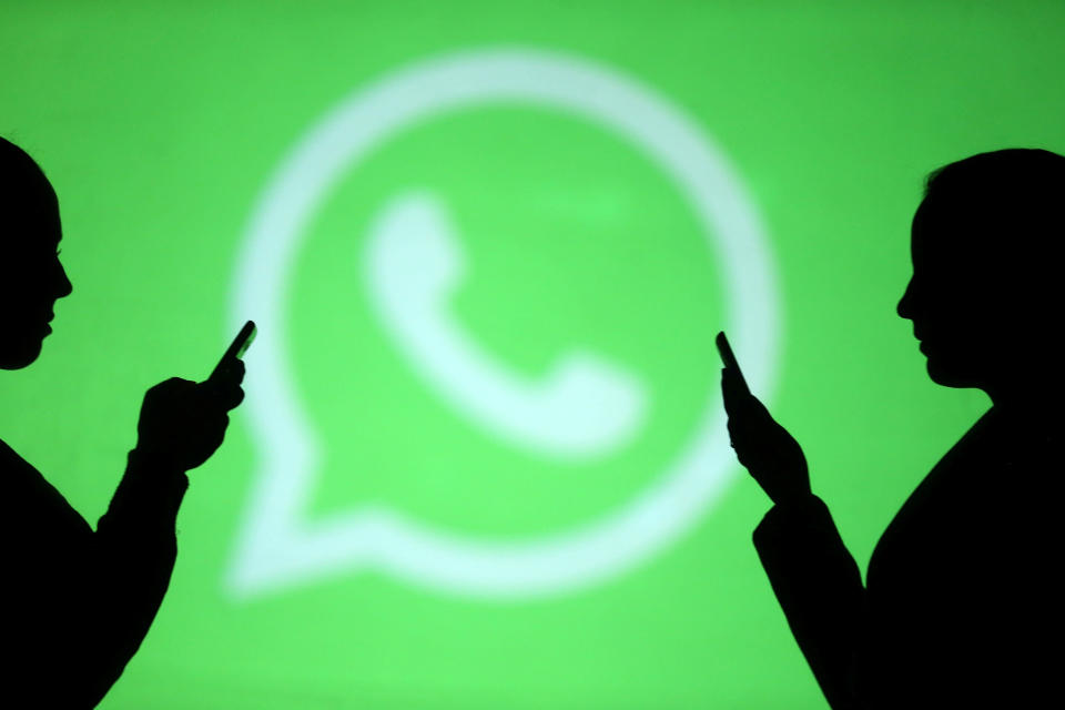 Silhouettes of mobile users are seen next to a screen projection of Whatsapp logo in this picture illustration taken March 28, 2018.  REUTERS/Dado Ruvic/Illustration