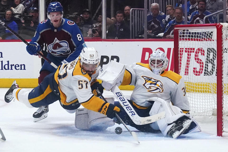 Nashville Predators defenseman Dante Fabbro (57) clears the puck from in front of goaltender Connor Ingram (39) as Colorado Avalanche defenseman Cale Makar (8) watches during the third period in Game 2 of an NHL hockey Stanley Cup first-round playoff series Thursday, May 5, 2022, in Denver. The Avalanche won 2-1. (AP Photo/Jack Dempsey)