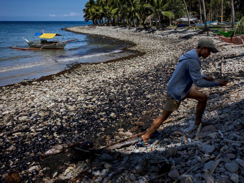 A resident walks along a shore covered in oil slick on March 8 in Pola, Oriental Mindoro.