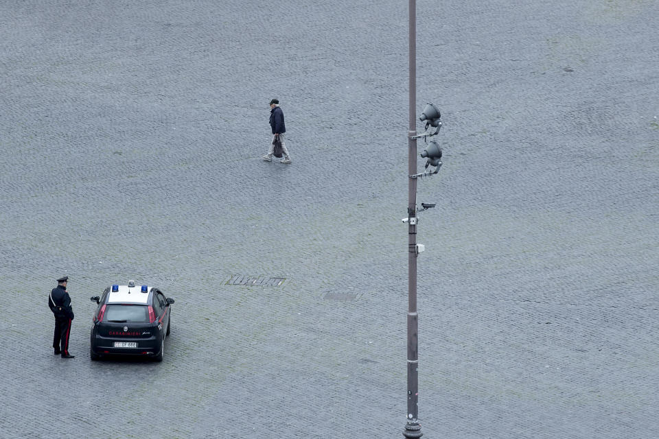 A policeman keeps an eye on rare passerby's in Rome, Saturday, March 14, 2020. A sweeping lockdown is in place in Italy to try to slow down the spread of coronavirus epidemic. For most people, the new coronavirus causes only mild or moderate symptoms. For some, it can cause more severe illness, especially in older adults and people with existing health problems. (Roberto Monaldo/LaPresse via AP)