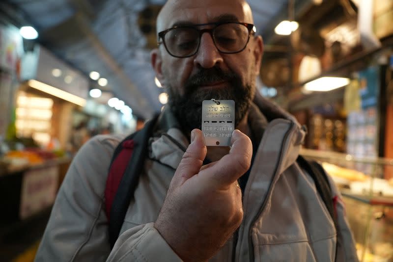 A man holds up a military-style dog tag calling for the return of Israeli hostages who have been held in the Gaza Strip since they were seized by Hamas gunmen on October 7, at Mahane Yehuda market in Jerusalem