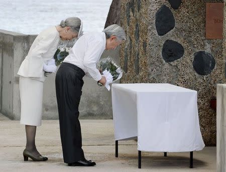 Japan's Emperor Akihito (R) and Empress Michiko bow as they offer flowers to the cenotaph for the war dead in the western Pacific area, on Palau's Peleliu Island, in this photo released by Kyodo April 9, 2015. Mandatory Credit REUTERS/Kyodo