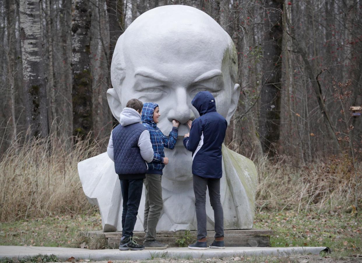 In this Friday, Oct. 27, 2017, photo, pupils play at a statue of Soviet Union founder Vladimir Lenin at the Lenin Hut Museum in a forest near Razliv Lake, outside St. Petersburg, Russia. The country marked the 100th anniversary of the Boshevik revolution that year.