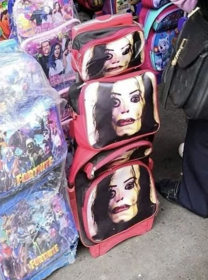 Stacked children's backpacks with distorted print of a female character's face from media