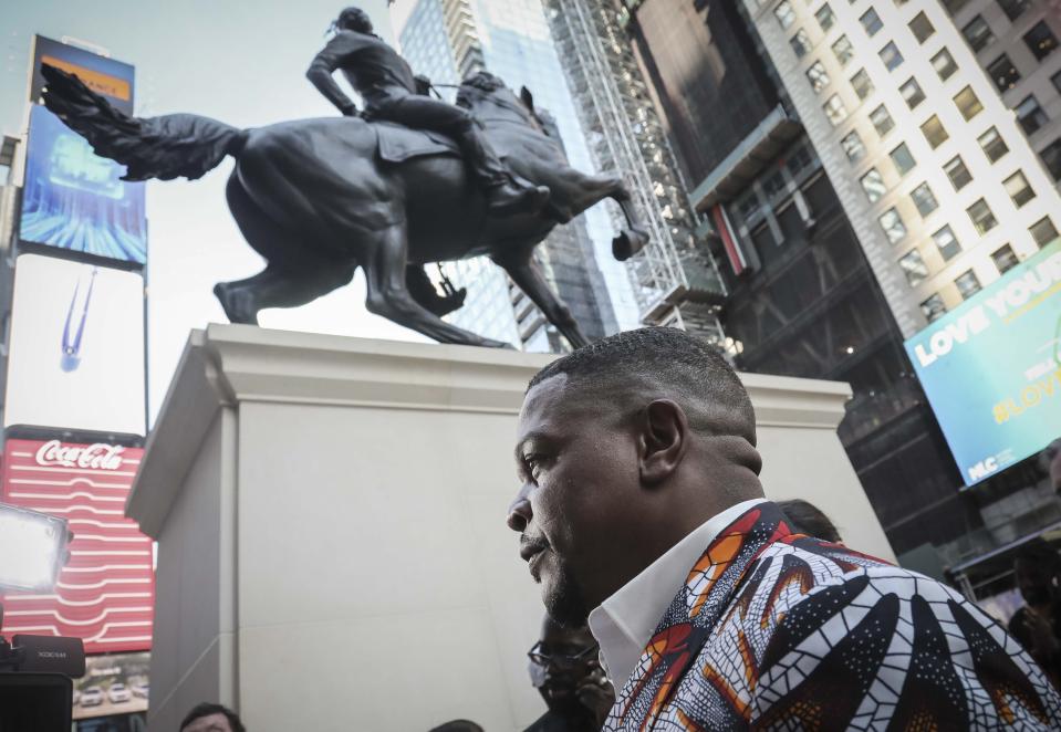 Visual artist Kehinde Wiley, best known for his portrayals of contemporary African-American and African-Diasporic individuals, appears at the unveiling his first monumental public sculpture "Rumors of War," an equestrian portraiture of warfare and heroism, Friday Sept. 27, 2019, in New York. The work will be exhibited in Times Square through December 1. (AP Photo/Bebeto Matthews)
