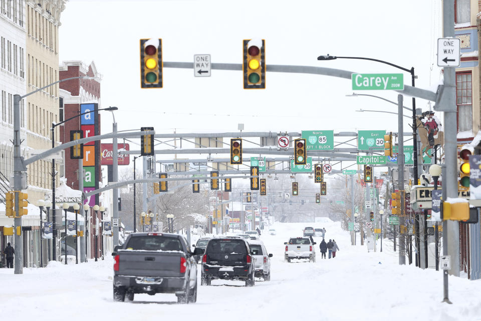 FILE - In this March 15, 2021 file photo, cars and pedestrians travel down West Lincoln way in downtown Cheyenne, Wyo., on Monday, March 15, 2021. Lawmakers are trying to stop 144 cities across the U.S. from losing their designations as “metropolitan areas” because the federal government is upgrading the standard from a minimum of 50,000 residents in its core to a minimum of 100,000 people. Cheyenne is among the cities at risk of losing the designation (Michael Cummo/The Wyoming Tribune Eagle via AP, File)