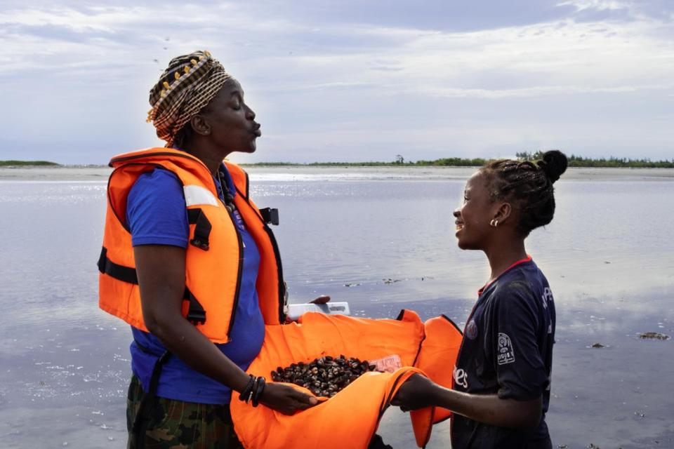 Coumba Dieng, an MSI team member with a young girl from a fishing community, holding cockles that they collected (Randa Osman/MSI Reproductive Choices)