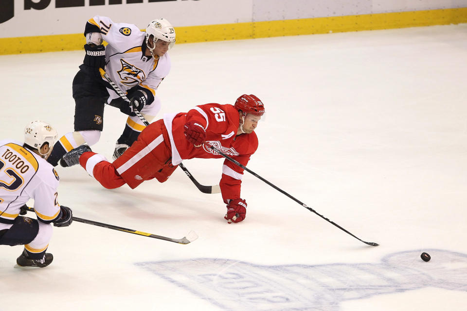 DETROIT, MI - APRIL 15: Niklas Kronwall #55 of the Detroit Red Wings dives for the puck in front of Sergei Kostitsyn #74 of the Nashville Predators during Game Three of the Western Conference Quarterfinals during the 2012 NHL Stanley Cup Playoffs at Joe Louis Arena on April 15, 2012 in Detroit, Michigan. (Photo by Gregory Shamus/Getty Images)