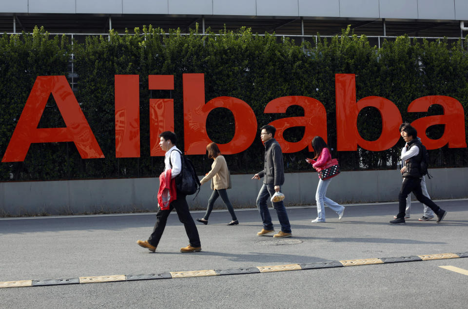 FILE - In this March 17, 2014 file photo, people walk past a company logo at the Alibaba Group headquarters in Hangzhou, in eastern China's Zhejiang province. Office Depot and Alibaba.com are creating a co-branded online store to expand the reach of both companies with small and medium size businesses. The two companies announced the agreement Monday, March 4, 2019, as part of a broader array of services they are providing to small business. Over time, the companies intend to help U.S. small businesses sell their products to buyers around the world through Alibaba.com. It marks Alibaba.com’s first U.S. partnership with a major company. (Chinatopix via AP, File)