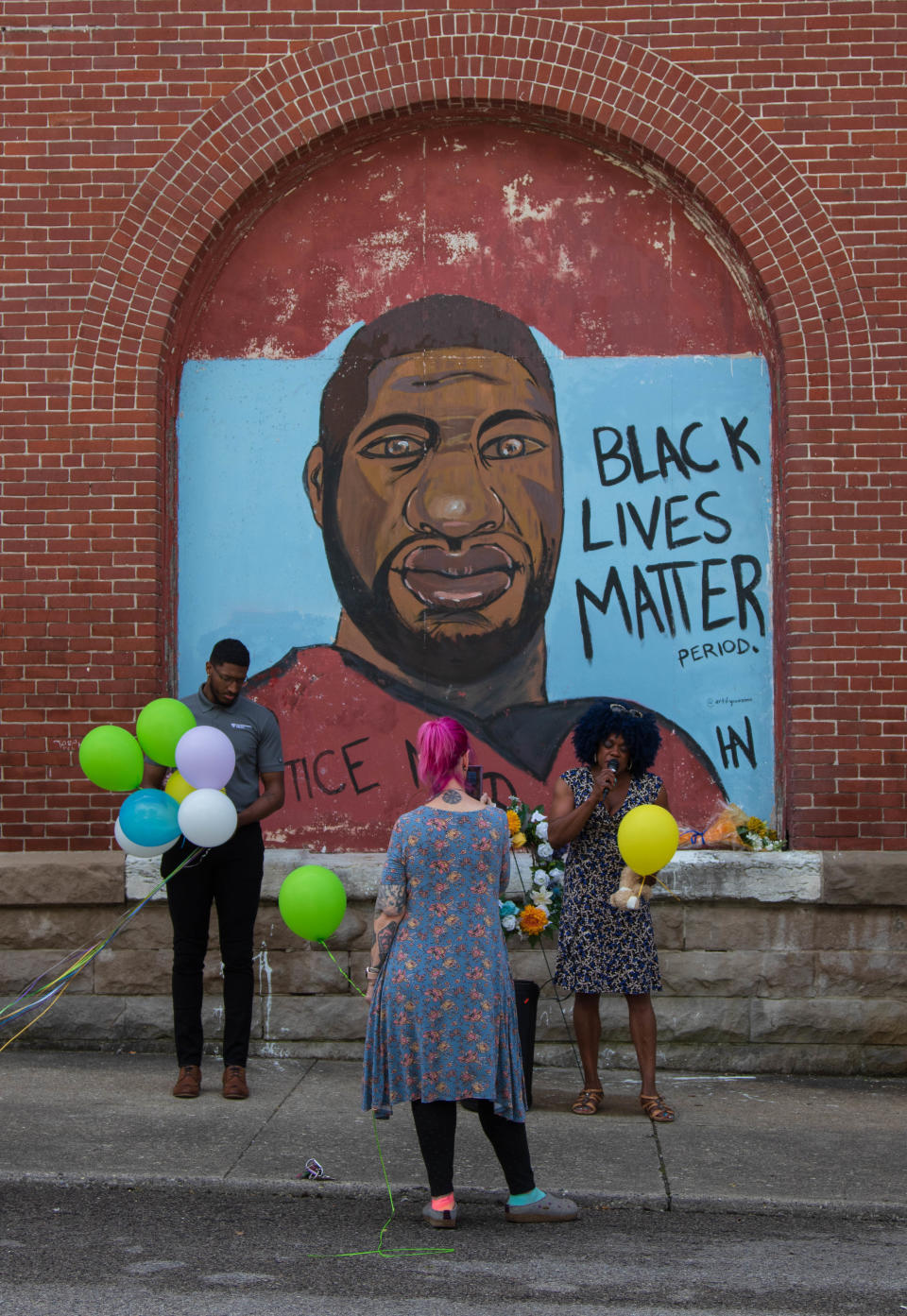 Khalil Williams and Paula Davis, the owner of Blooms & Petals, pray for George Floyd and the victims of the Buffalo and Uvalde shooting, at the George Floyd mural on May 25, 2022, in Lafayette.