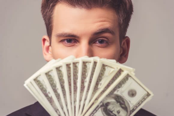 Man holding money fanned out in front of his face